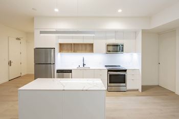 A modern kitchen with a refrigerator, microwave, oven, and sink.